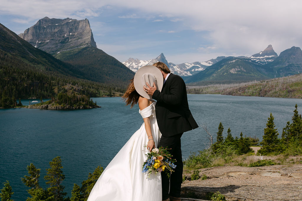 Newlyweds embracing beside the mountains in Glacier National Park.