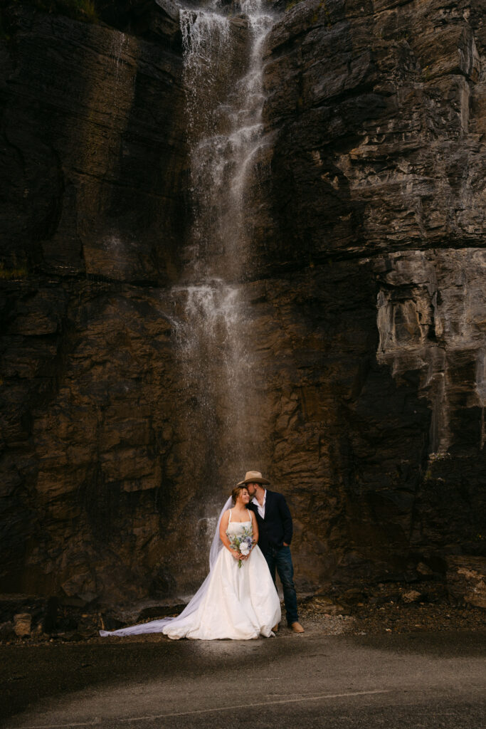 Bride standing in front of a waterfall during her Glacier National Park wedding