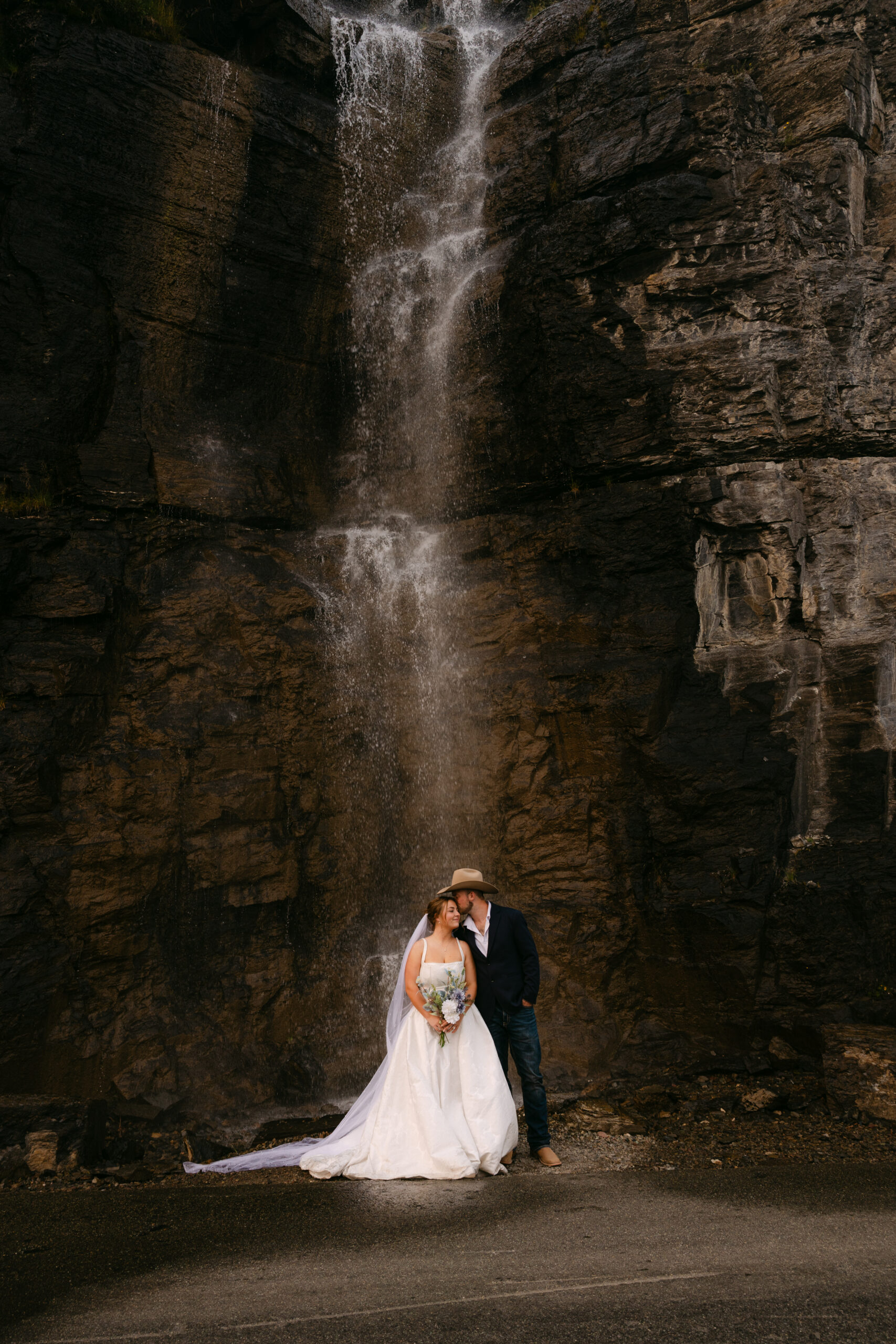 Bride standing in front of a waterfall during her Glacier National Park wedding